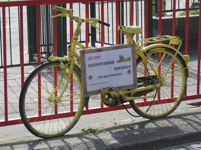 908187 Afbeelding van een geel geschilderde oude fiets met een waarschuwingsbord voor overstekende kinderen, vastgezet ...
